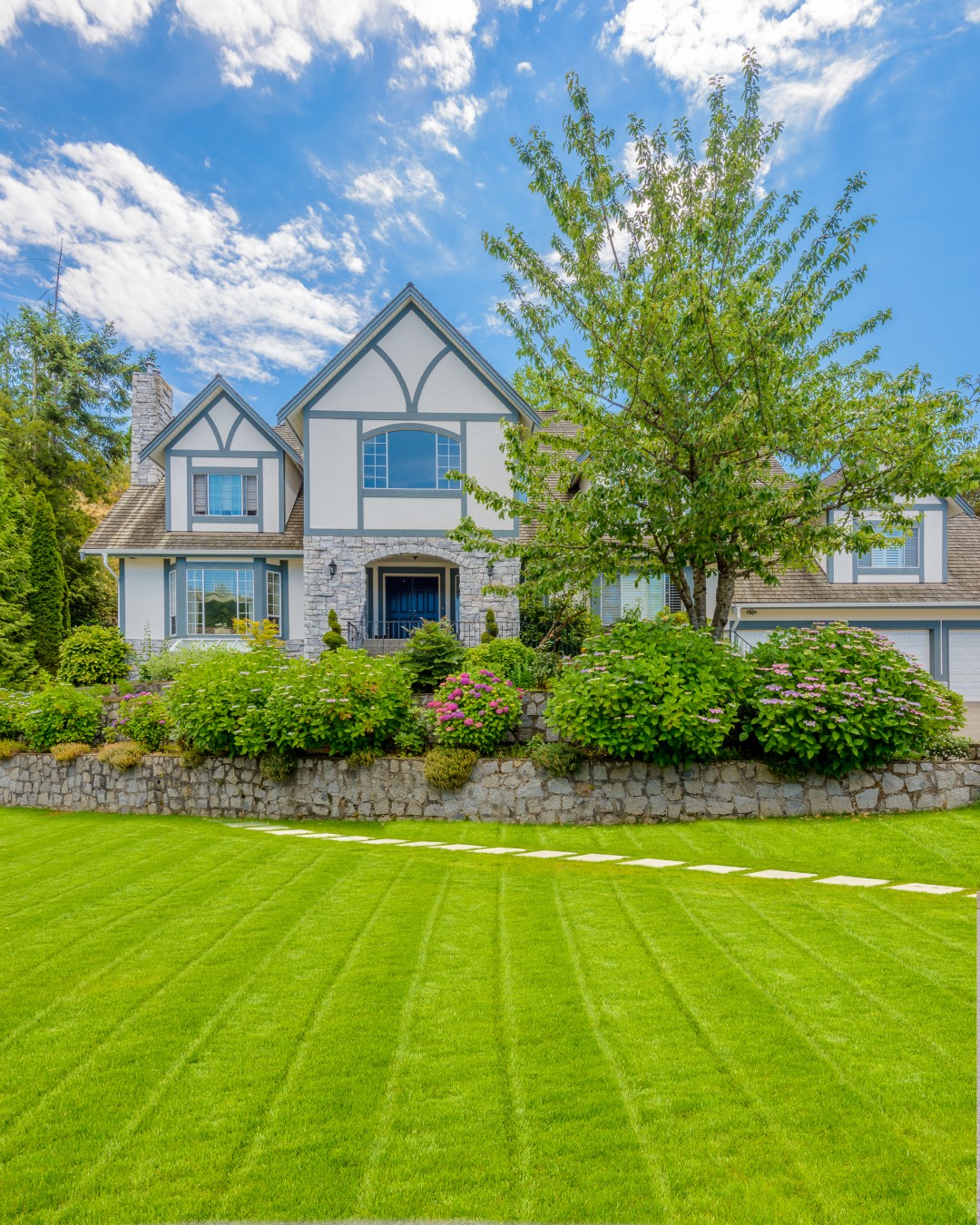 beautiful photo of a front yard with a lawn, stepping stones, and shrubs